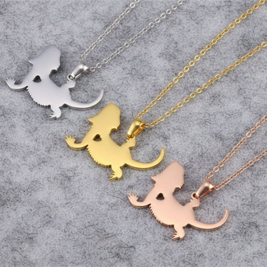 Three dinosaur-shaped pendants on necklaces in silver, gold, and rose gold 