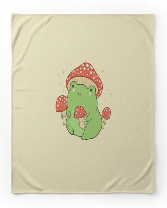 a large cream-colored blanket or throw featuring a cartoon green frog wearing a red-and-white polka dot mushroom hat, shown against a plain white background.
