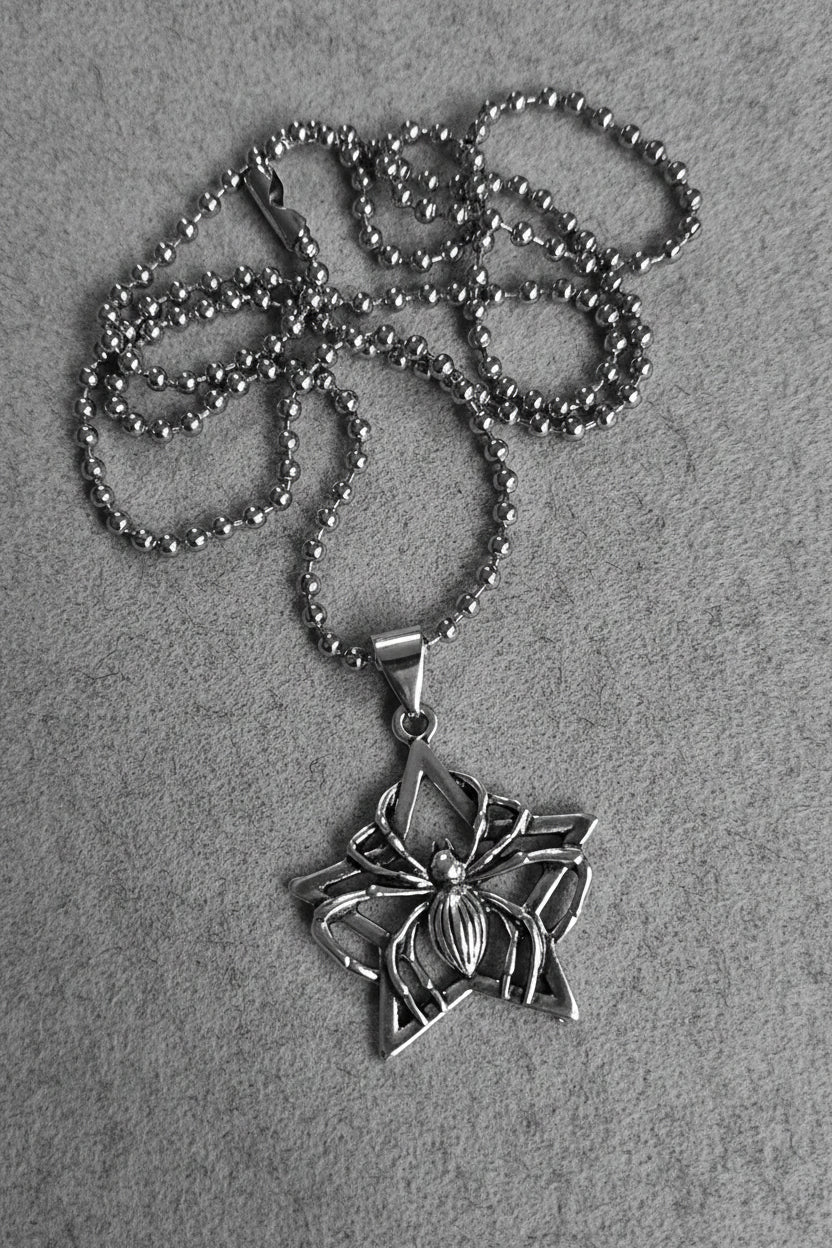 Silver spider pendant necklace on a light gray background