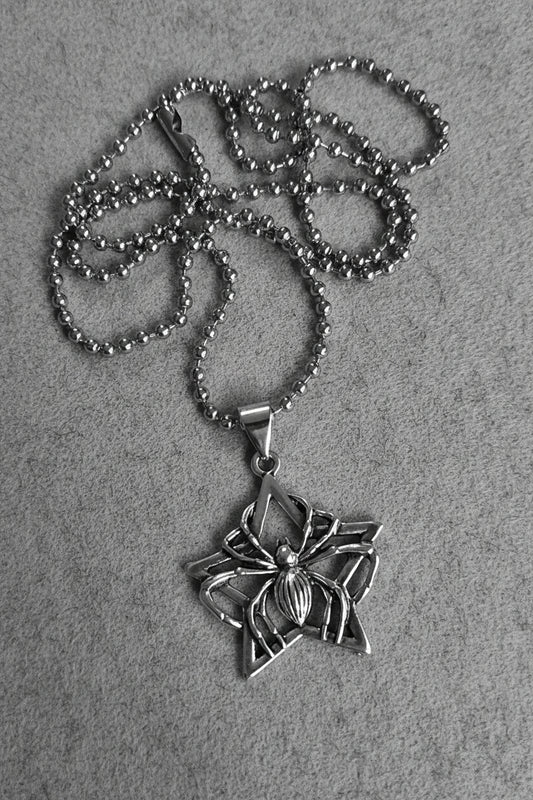 Silver spider pendant necklace on a light gray background