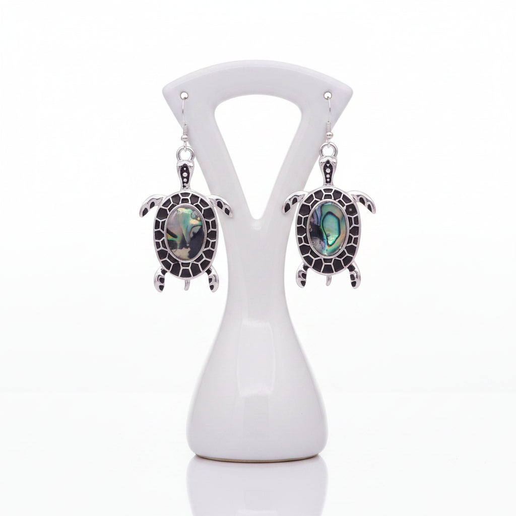 Turtle-shaped earrings with abalone shell inlays on a white background