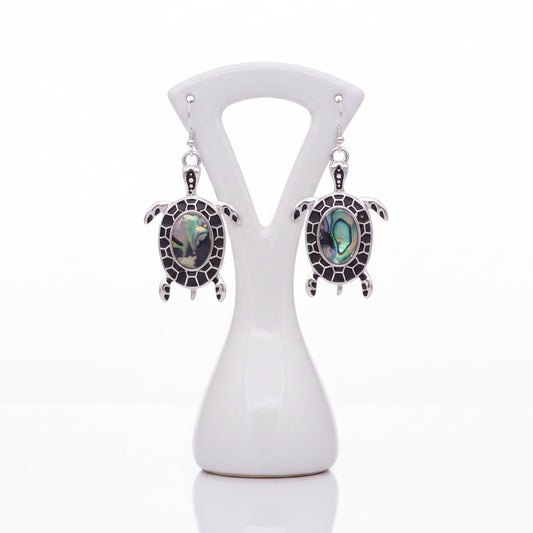 Turtle-shaped earrings with abalone shell inlays on a white background